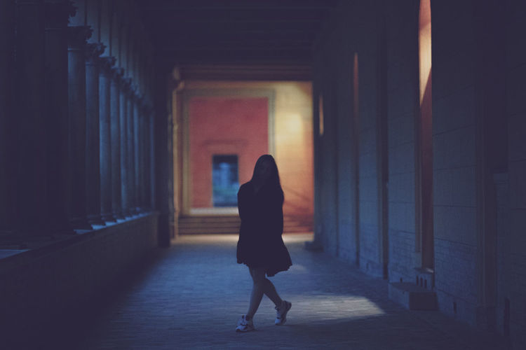 Full length of young woman standing in dark corridor