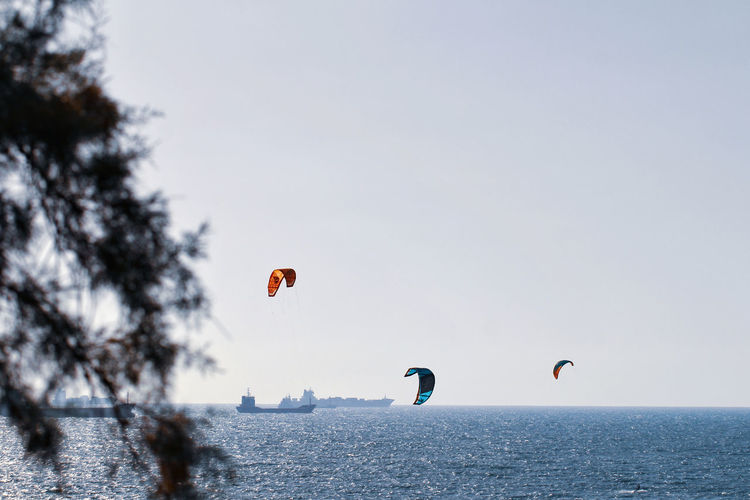 People paragliding over sea against clear sky