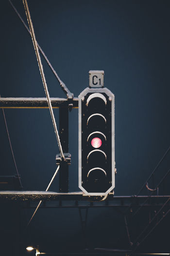 Low angle view of illuminated red light signal against sky during winter