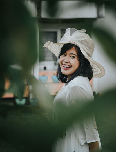 Portrait of cheerful young woman wearing hat standing outdoors