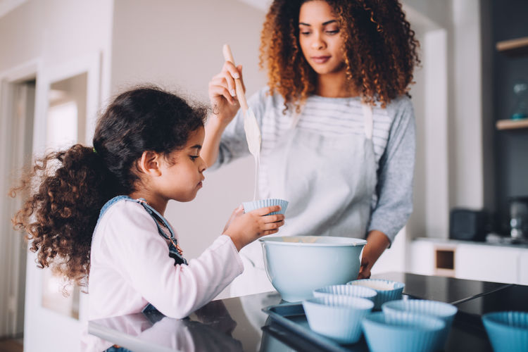Mother and daughter preparing food in kitchen at home