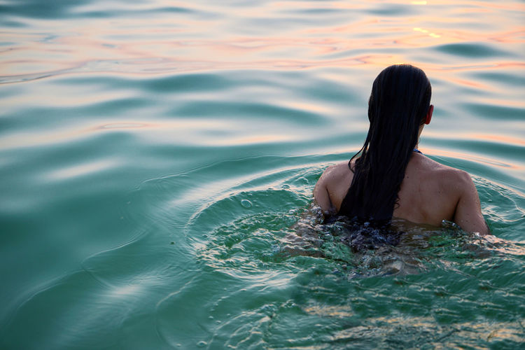 Woman swimming in the sea at sunset