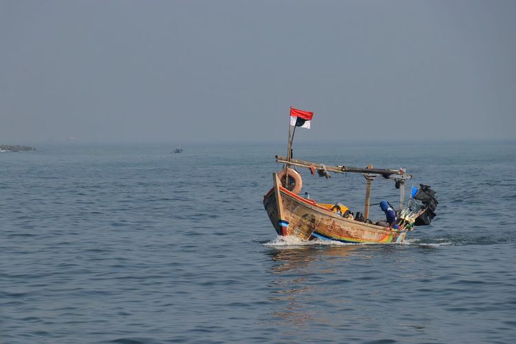 Fishing boat in sea against clear sky