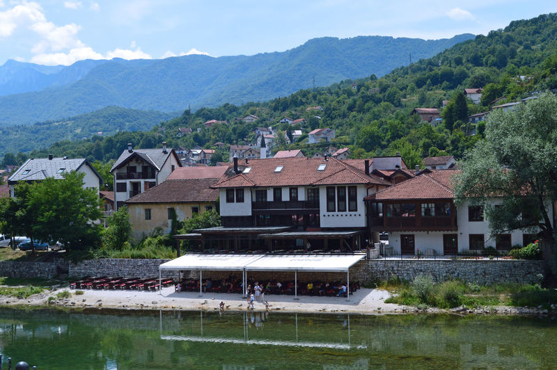 Houses by lake and buildings against sky