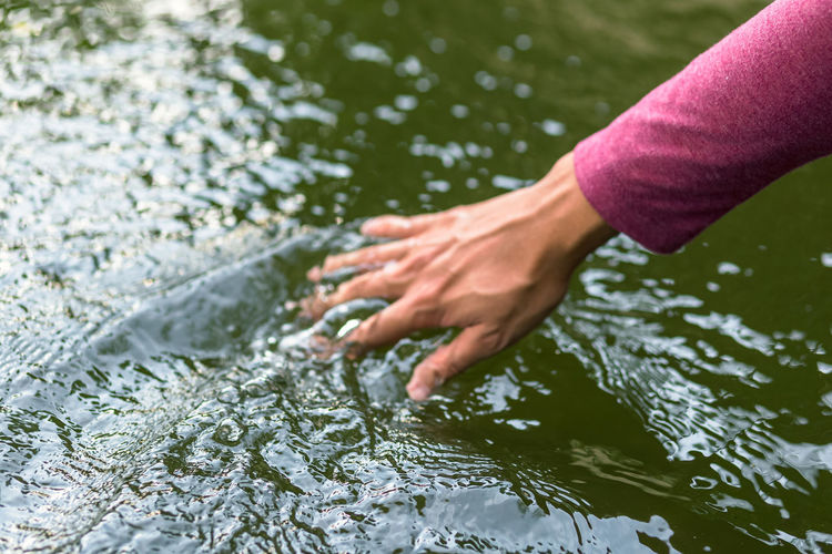 Close-up of woman touching water in lake
