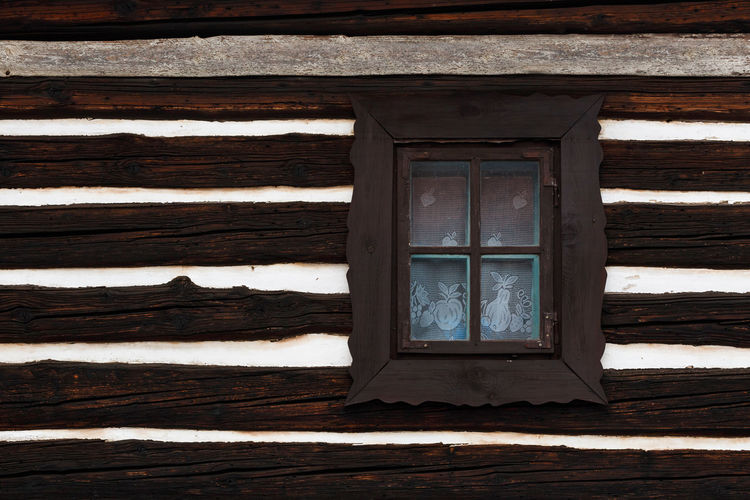 Window and a wall of a traditional wooden cottage in a village.