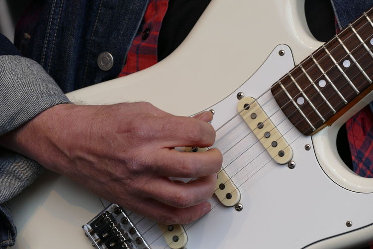 Close-up mid section of a man playing guitar