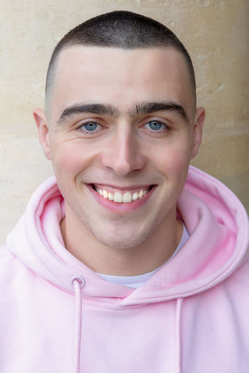 Portrait of smiling young man against pink wall