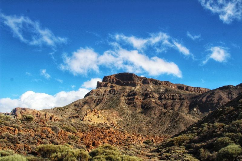 Scenic view of rocky mountains against blue sky