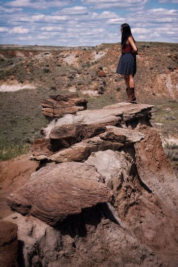 Side view of woman standing on hoodoo rock in badlands 