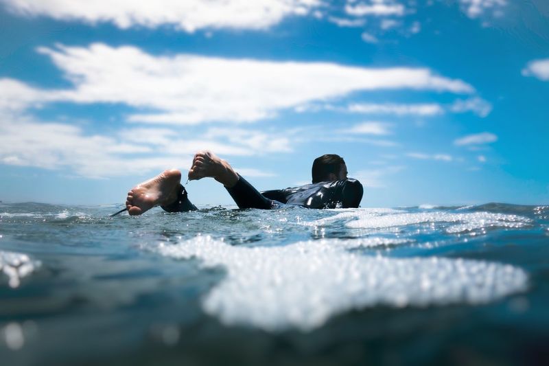 People swimming in sea against sky