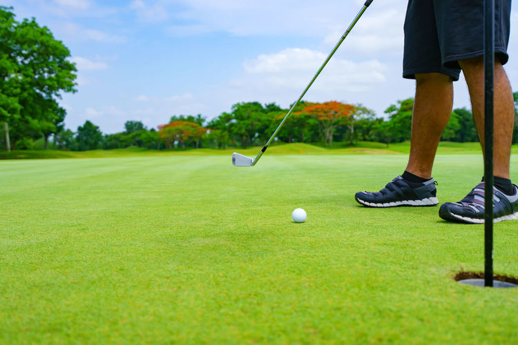 Low section of man playing golf on field