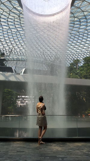 Rear view of woman standing by fountain in city