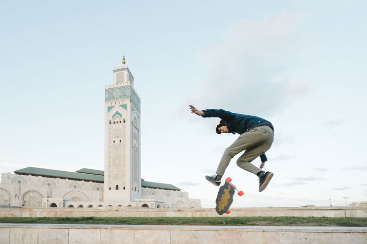 Side view of man skateboarding against mosque hassan ii
