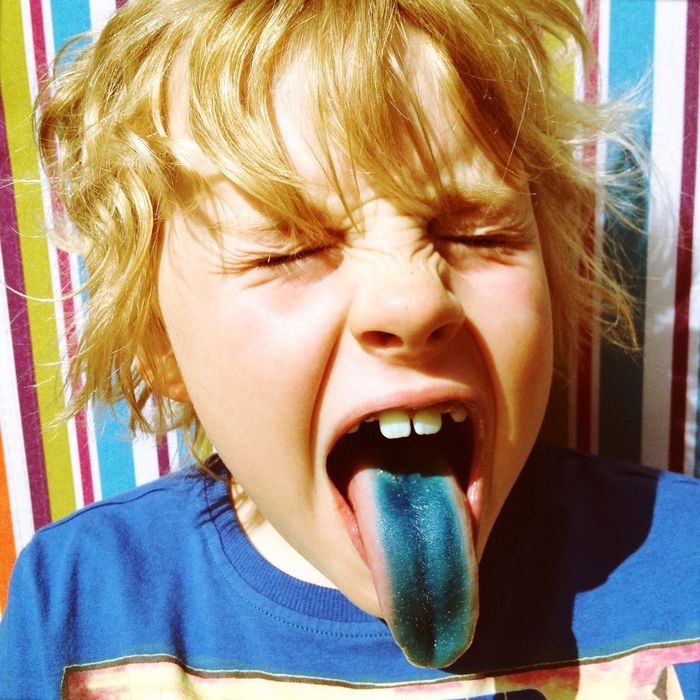 Close-up of blond boy with colored tongue