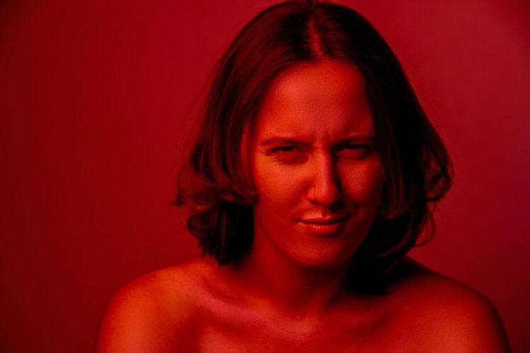 Close-up portrait of young woman against red background