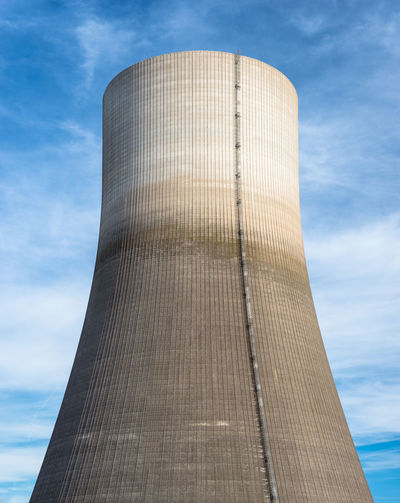 A huge chimney of a nuclear power plant close up on a background of blue sky with clouds