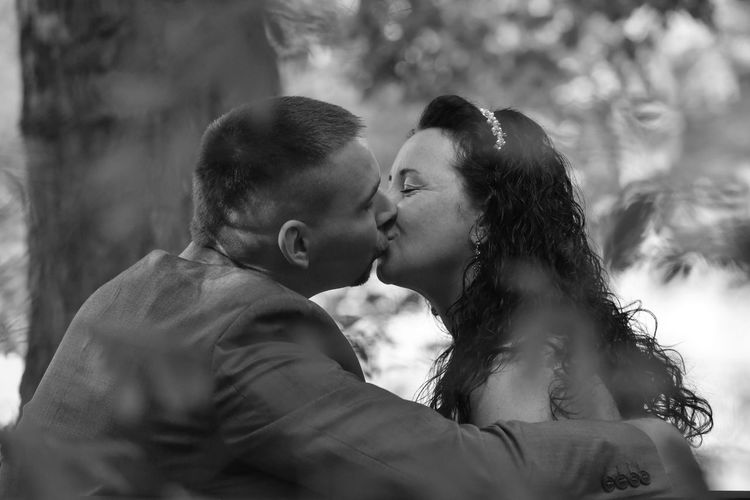 Close-up of couple kissing against trees