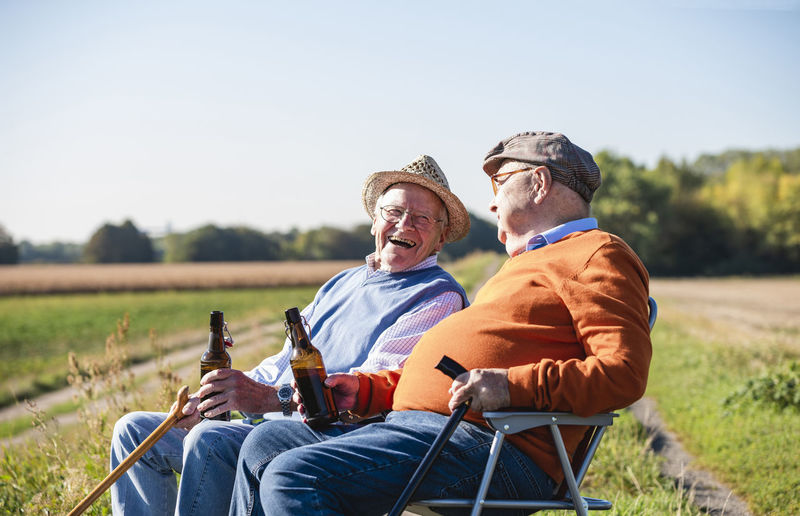 Two old friends sitting in the fields, drinking beer, talking about old times