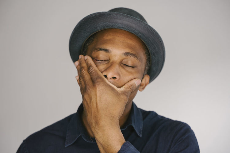 Portrait of young man wearing hat against white background
