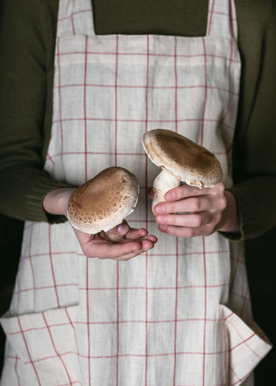 Girl's hands holding two raw whole organic champignons mushrooms. vegan, vegetarian food concept.
