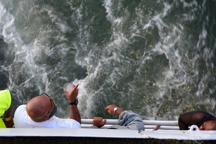 High angle view of people standing by railing in boat on sea