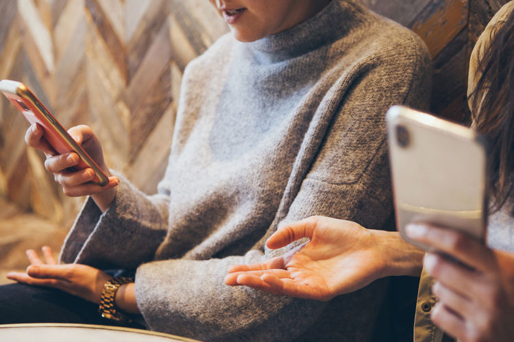 Midsection of women using mobile phone