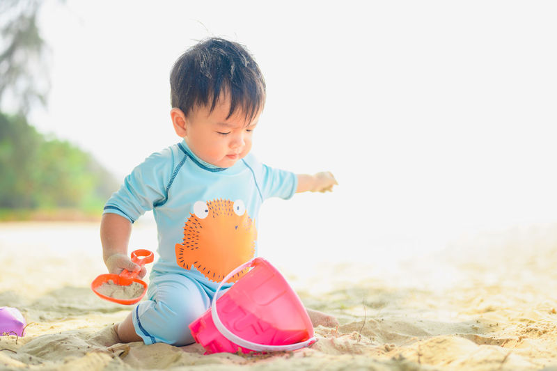 Cute girl playing with toy on sand