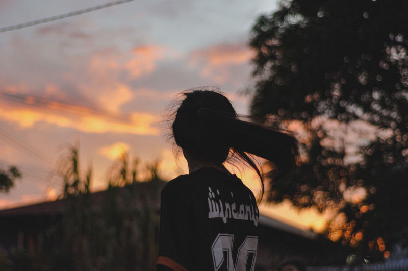 Rear view of silhouette woman against orange sky