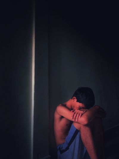 Young man looking away against wall