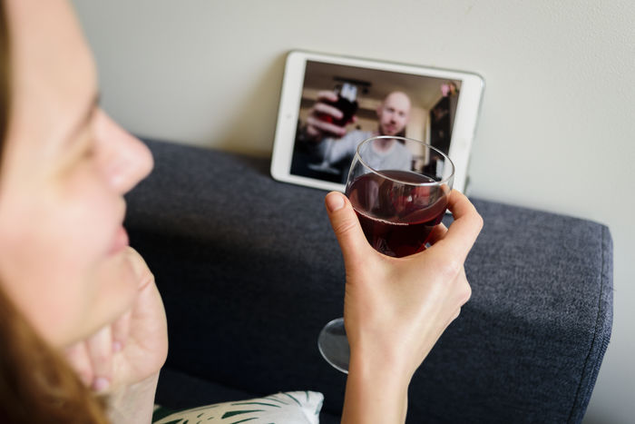 Woman toasting wineglass while doing video conference on digital tablet at home