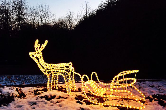 Illuminated reindeer sleigh on snowy landscape against clear sky