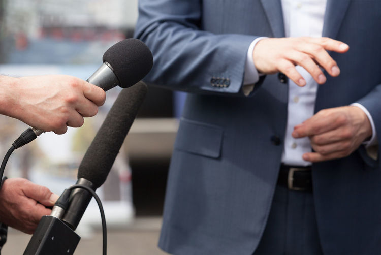 Cropped hands of journalists interviewing businessman