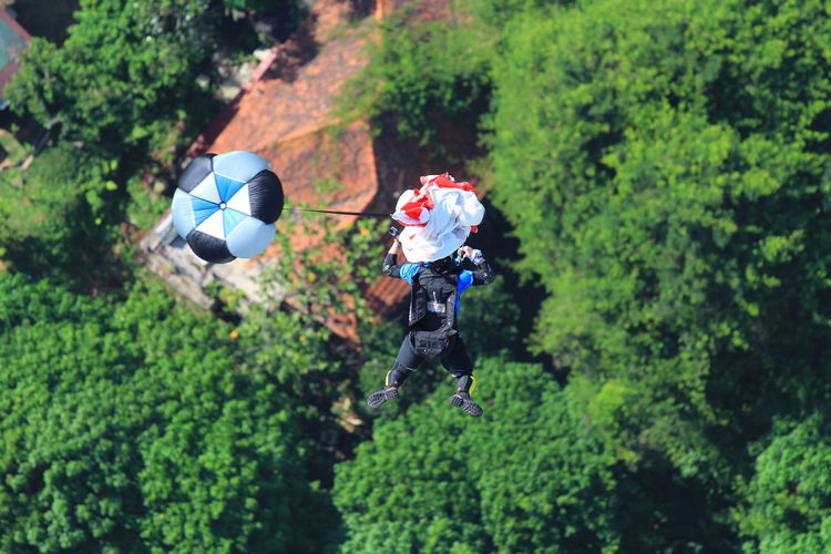 High angle view of man base jumping with against trees