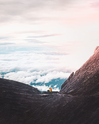 Hiker standing on mountain against sky