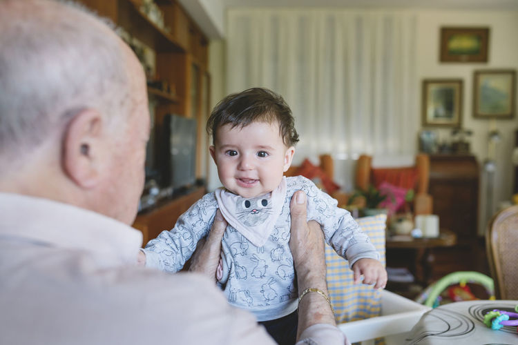 Great-grandfather holding a cute baby girl at home