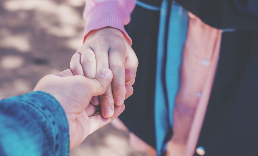 Cropped image of man holding hands with girlfriend on field