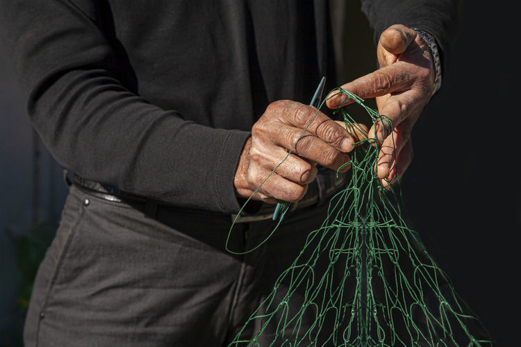 Midsection of man holding fishing net