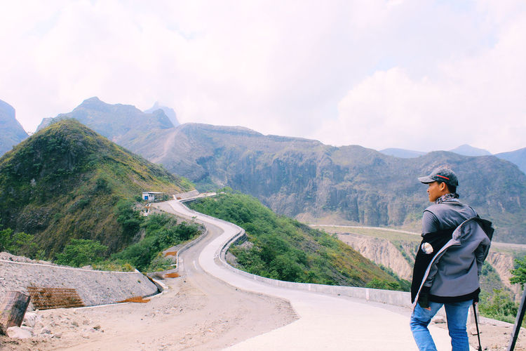 Man standing on road against mountain range