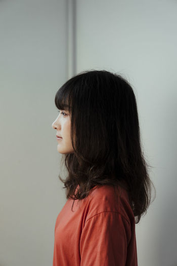 Sad woman looking away against wall
