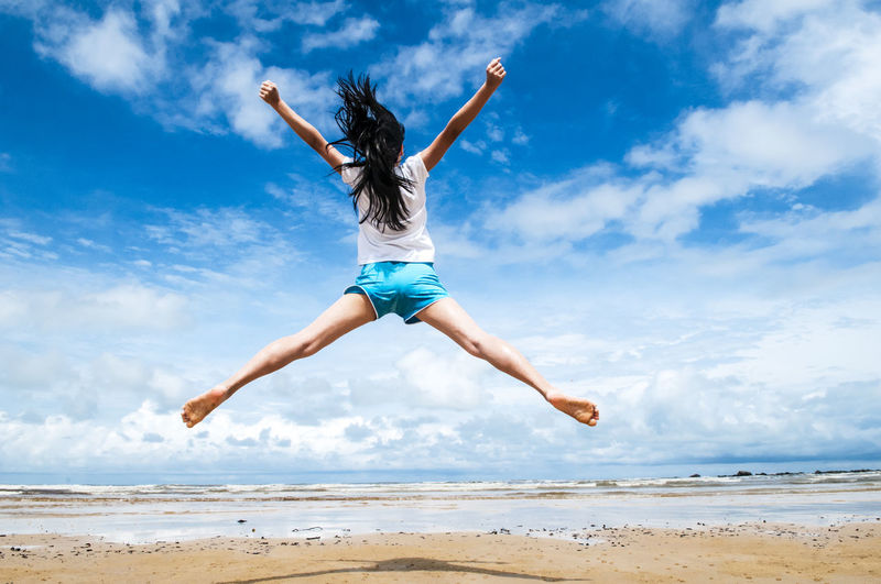 Low angle view of person jumping on beach against sky