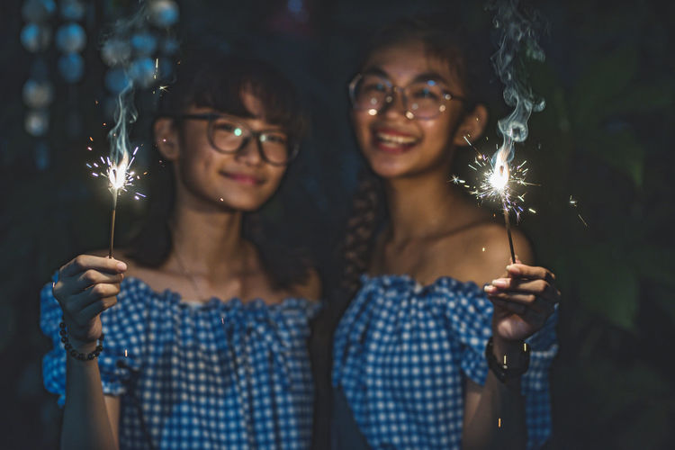 Portrait of smiling people holding sparklers at night