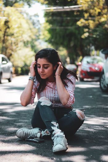 Young woman sitting on street in city