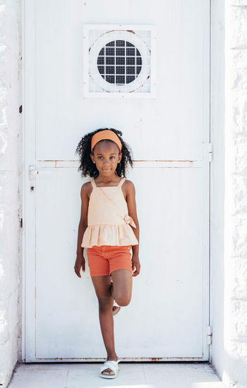 Smiling black girl looking at camera in metal door in sunny street