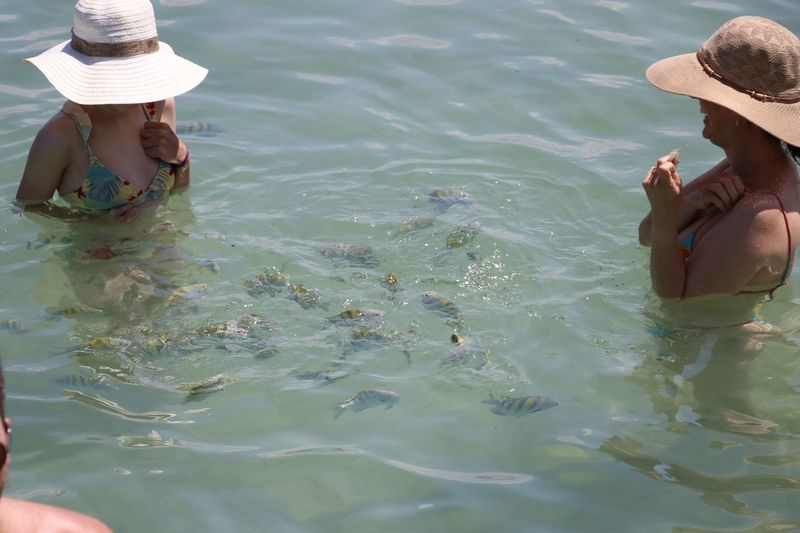 Mother and daughter standing by fish swimming in sea