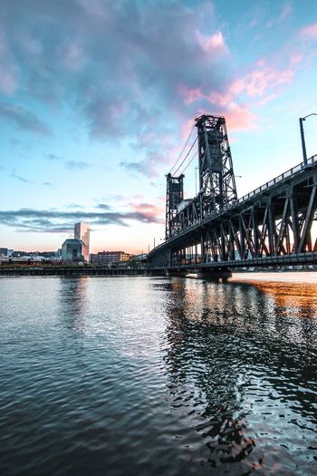 River by city against sky during sunset