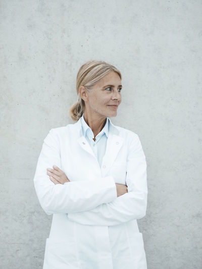 Female doctor standing against wall