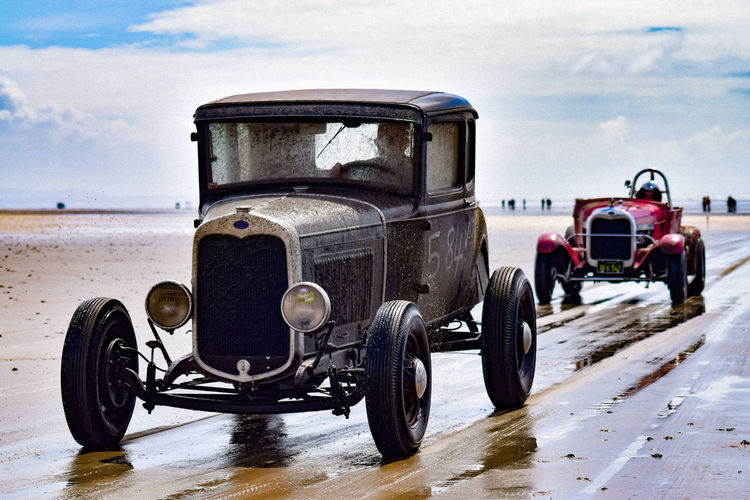 Vintage cars at beach against sky