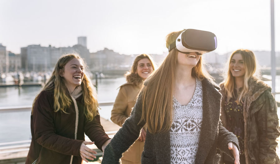 Teenage girl using wearing vr glasses while her friends watching her