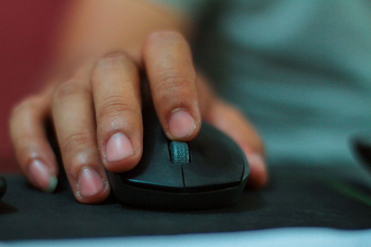 Cropped image of hand using computer mouse